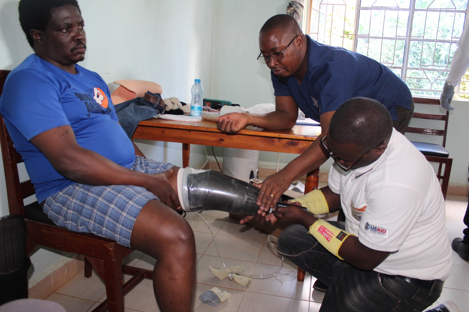 A senior orthopaedic technologist helping a patient to fit assistive device at Nyabondo Rehab Centre.